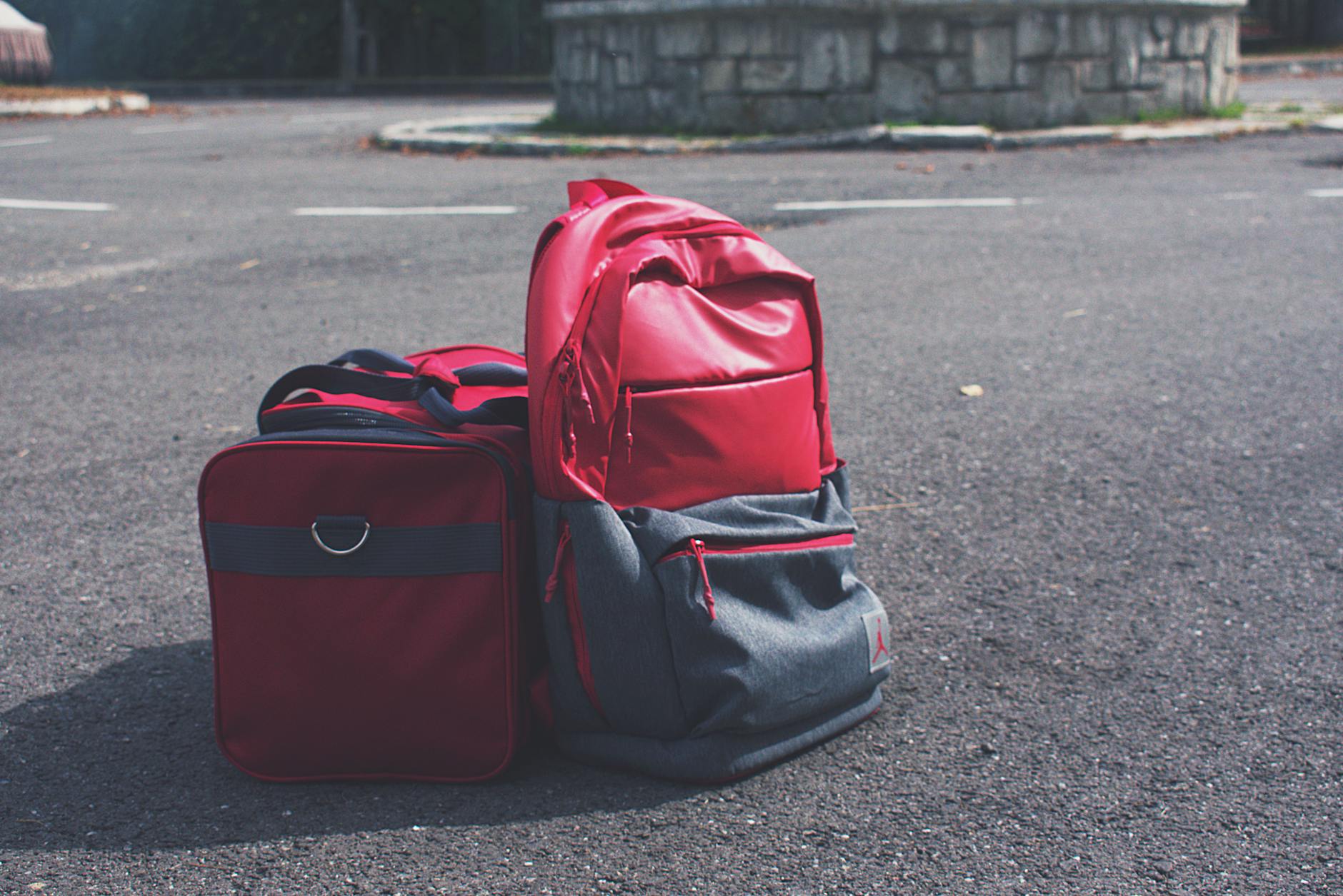 red and gray backpack beside red duffel bag