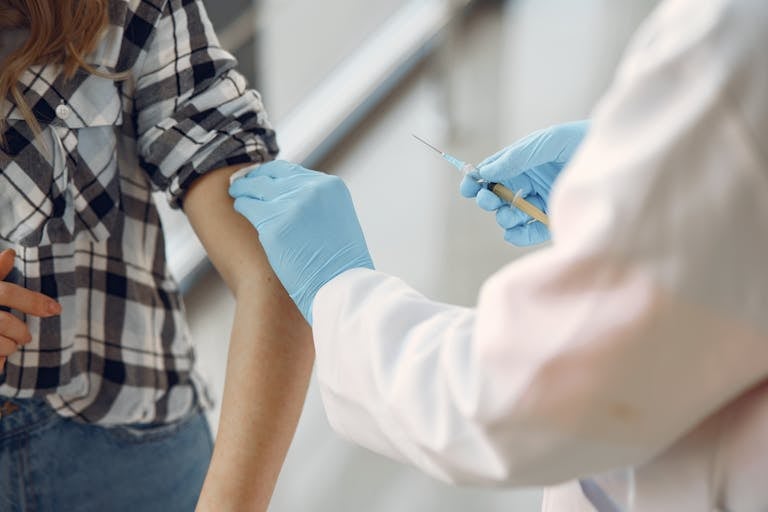 A medical professional giving a vaccination to a patient indoors, emphasizing healthcare.