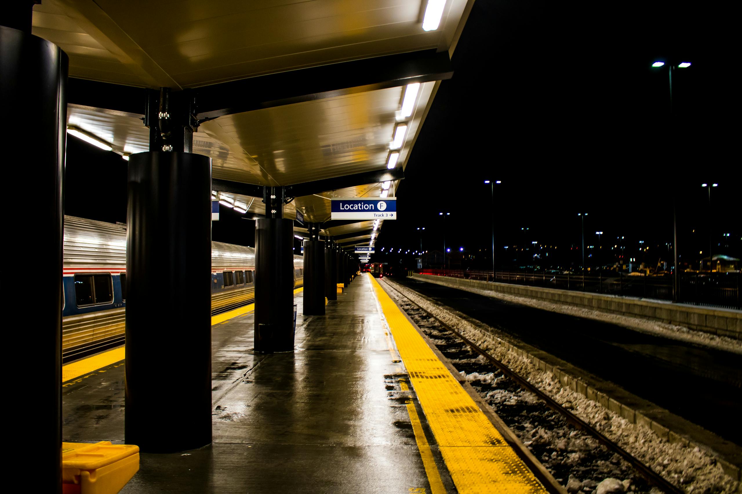 Illuminated train station platform at night with awaiting train.