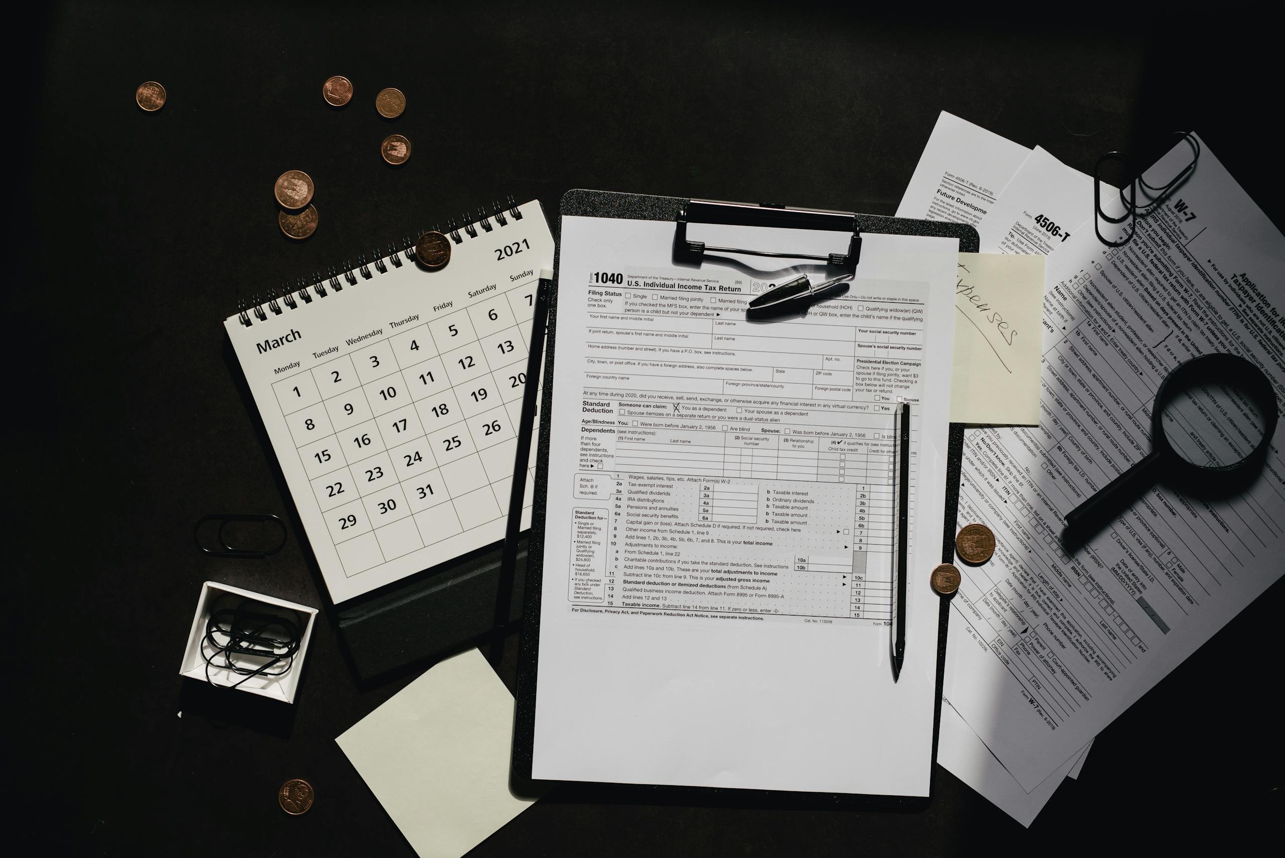 A neatly organized workspace featuring tax forms, calendar, magnifying glass, and office supplies for efficient tax preparation.