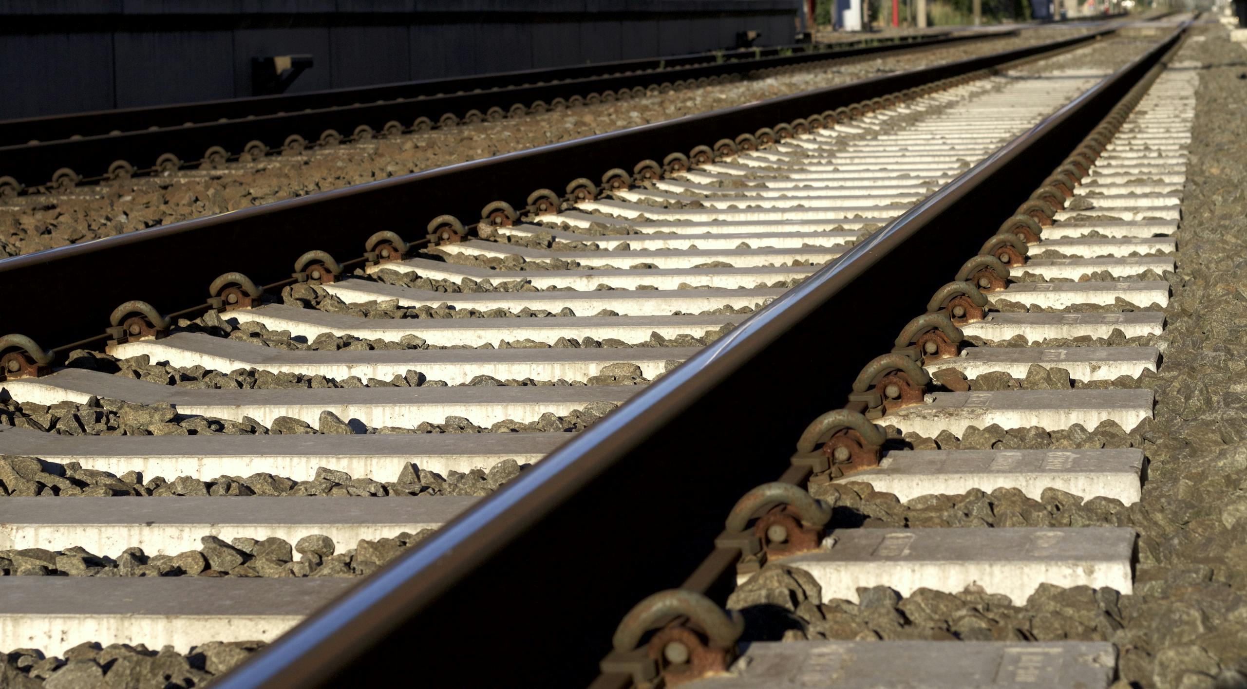 Detailed photo of railway tracks under bright sunlight with stones.
