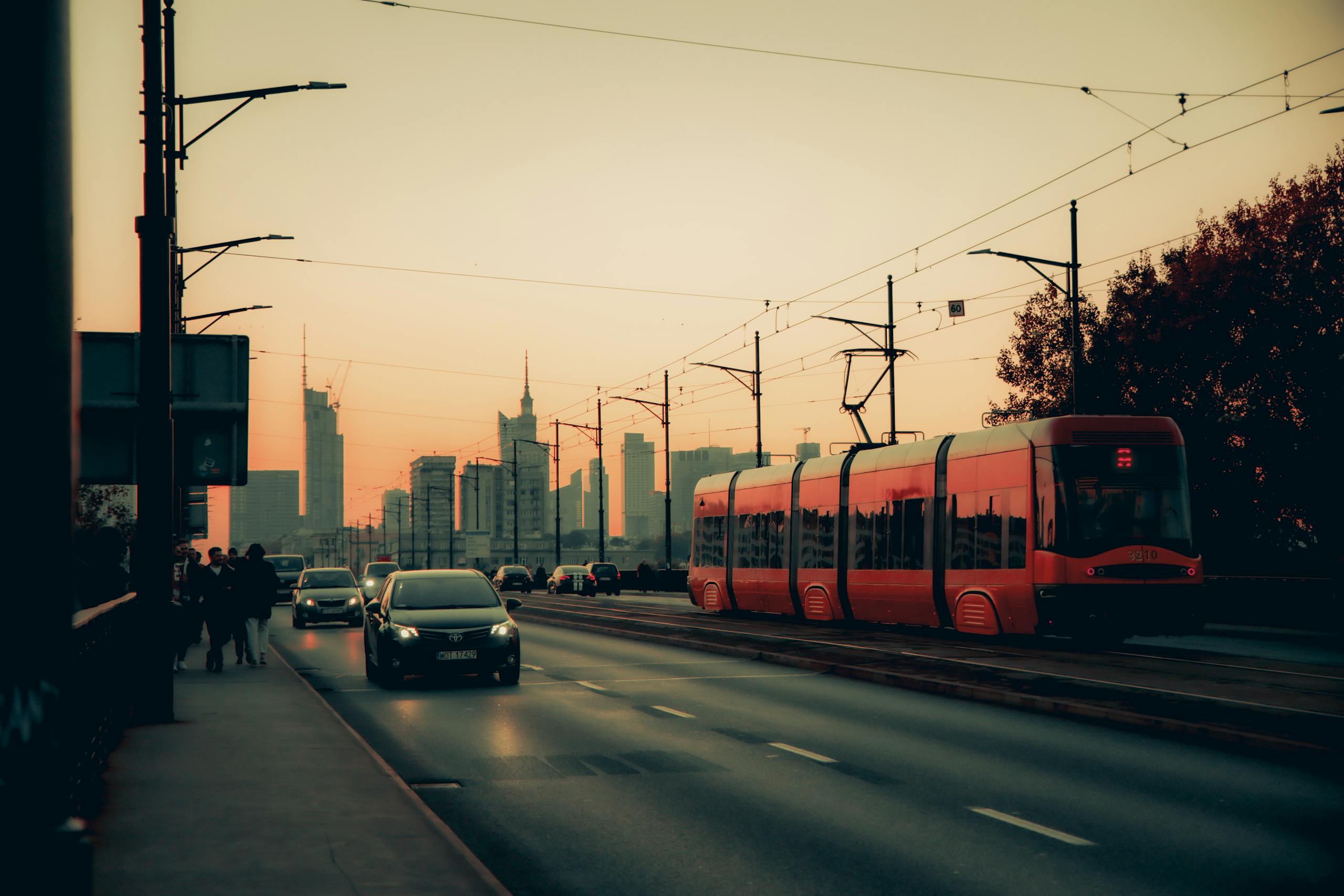 A vibrant sunset over Warsaw with a tram on the move, showcasing urban life and transportation.