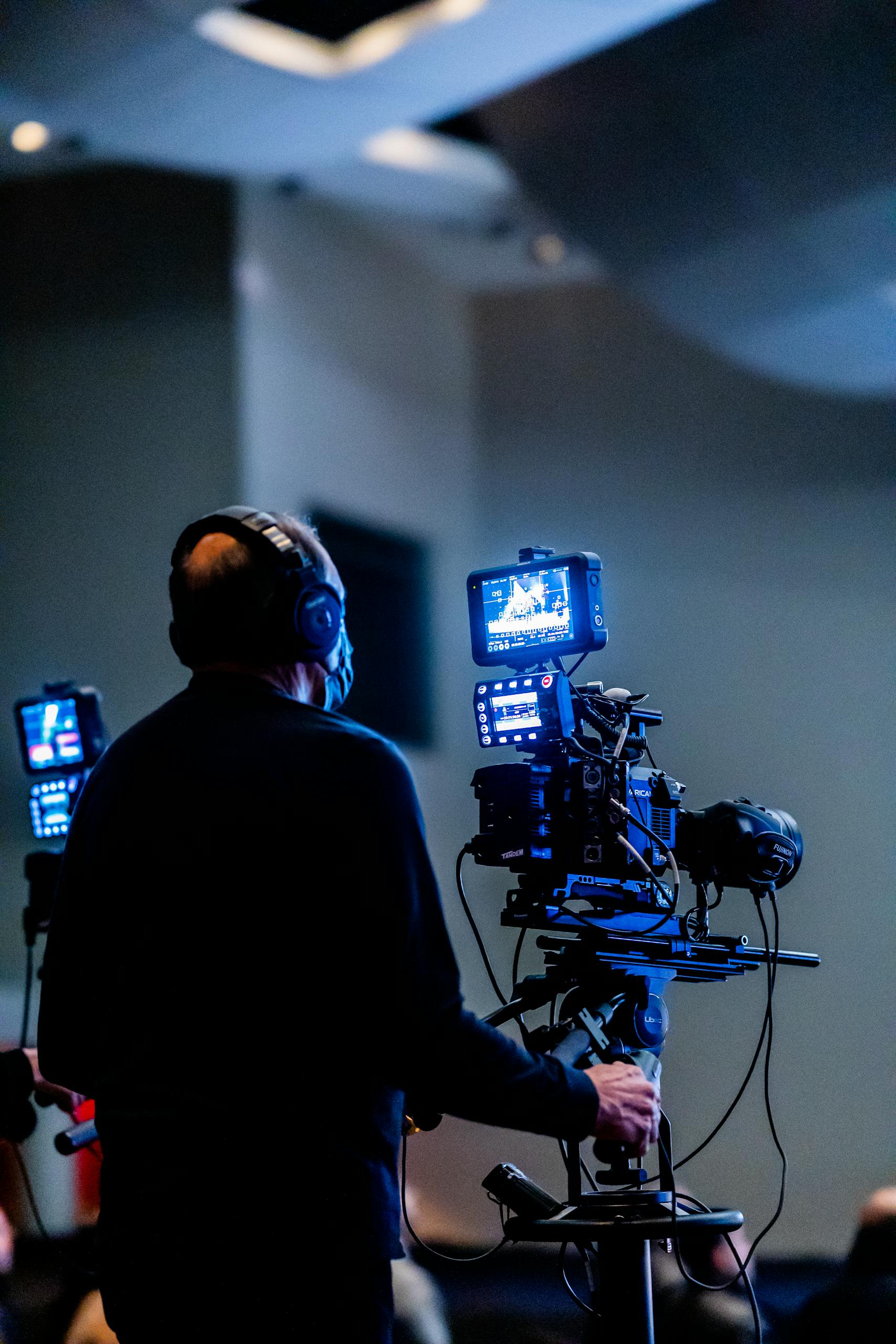Expert cameraman recording with high-tech video camera in a studio setting.
