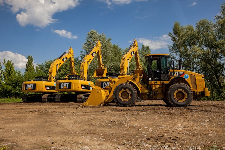 Four yellow excavators at an outdoor construction site in Kyiv, Ukraine.