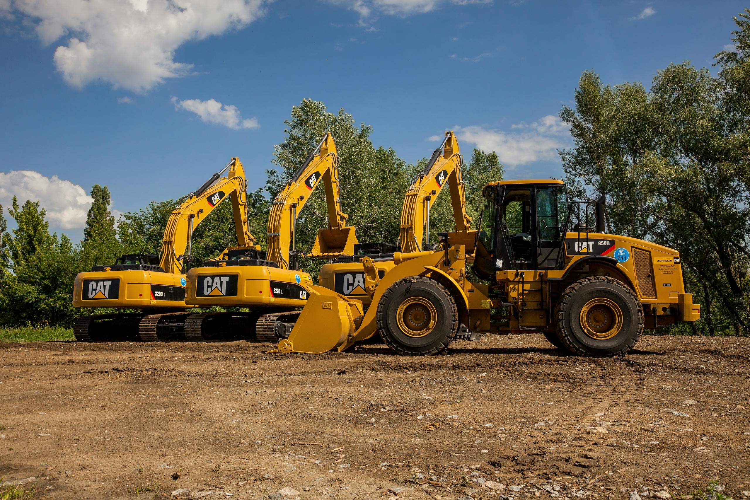 Four yellow excavators at an outdoor construction site in Kyiv, Ukraine.