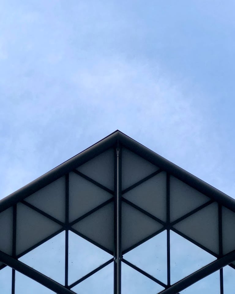 A striking modern building facade with geometric patterns against a clear blue sky in Łódź, Poland.