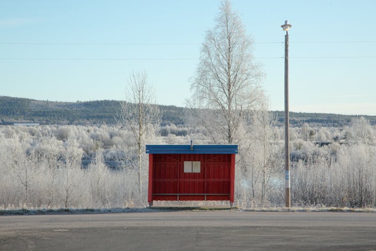 Red bus stop surrounded by frosty trees in Övertorneå, Sweden.