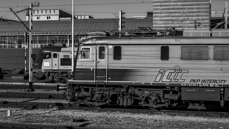 Black and white image of two PKP Intercity trains at a railway station.