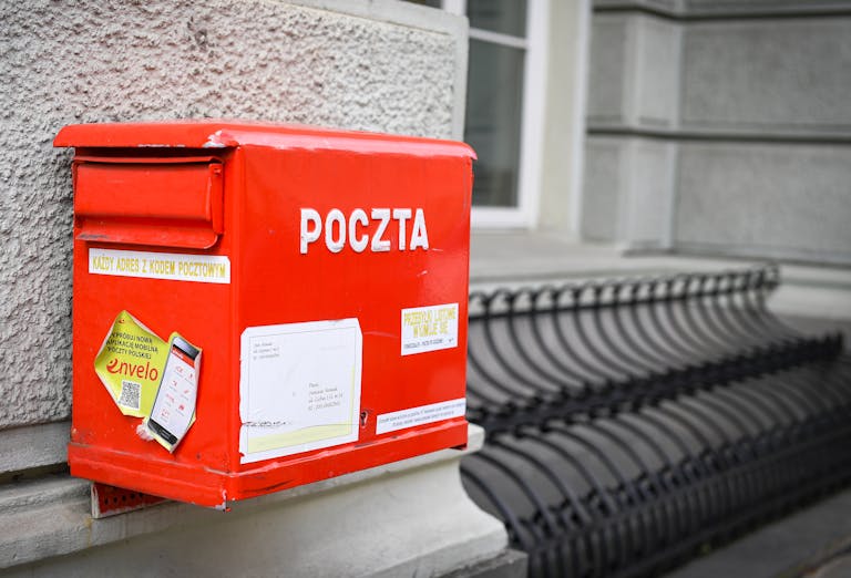 Close-up of a traditional red Polish mailbox on a historic street in Warsaw.