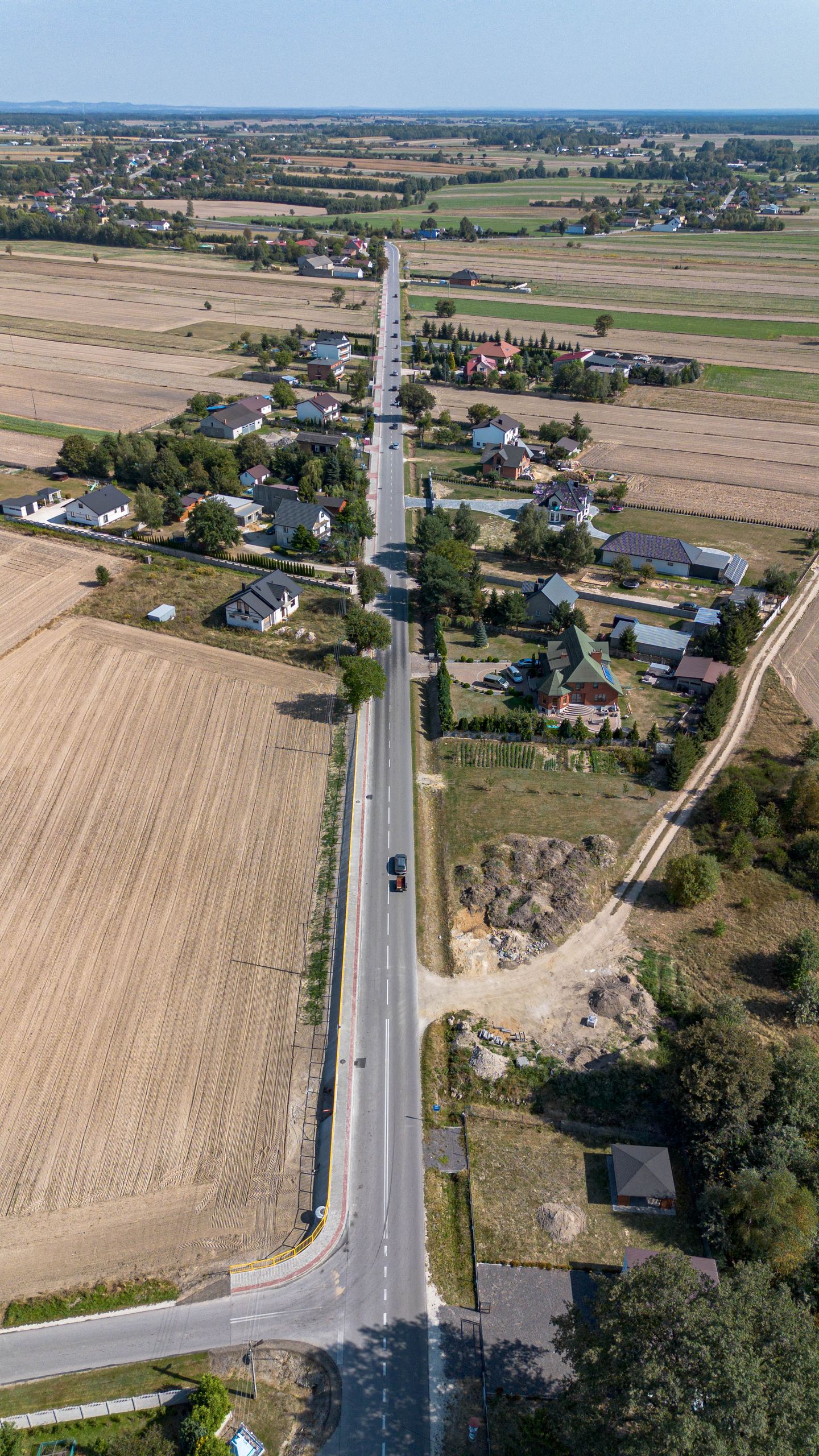 Aerial photo showcasing a long straight road amidst rural landscapes and fields.