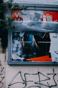 Vandalized urban billboard with graffiti and peeling posters.