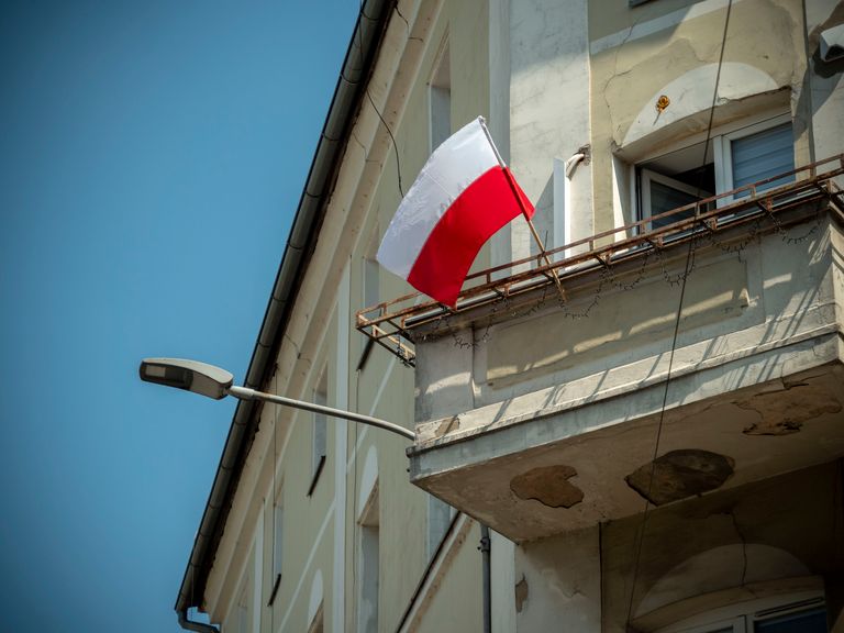 Polish flag waving on a balcony in Wrocław, Poland during a sunny day.